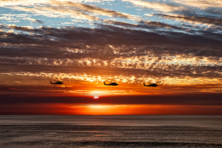 choppers over the ocean at sunset