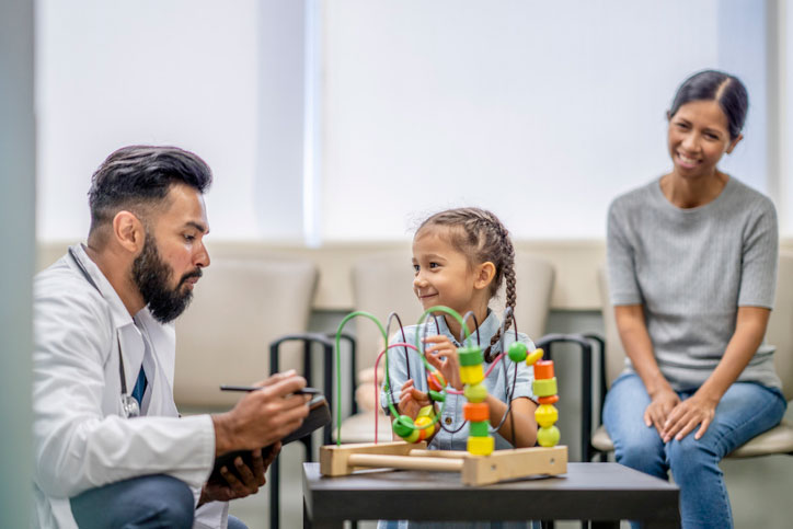 neuropsychologist playing games with young girl, while mom looks on