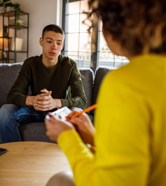 Caring female psychologist talking with insecure teenage boy